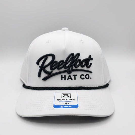 A white structured snapback cap with black embroidered 'Reelfoot HAT CO.' lettering on the front, a black rope detail under the brim, and a visible Richardson brand sticker on the brim, photographed on a light gray studio background.