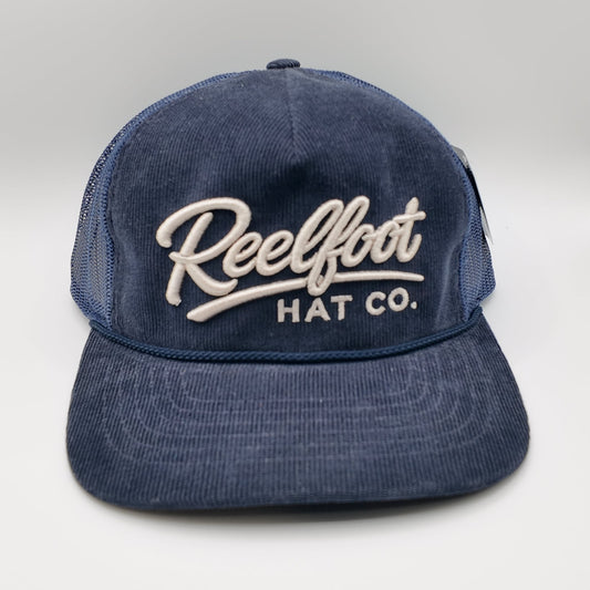 A navy blue corduroy trucker hat with white embroidered text reading 'Reelfoot HAT CO.' on the front, shown against a light gray studio background.